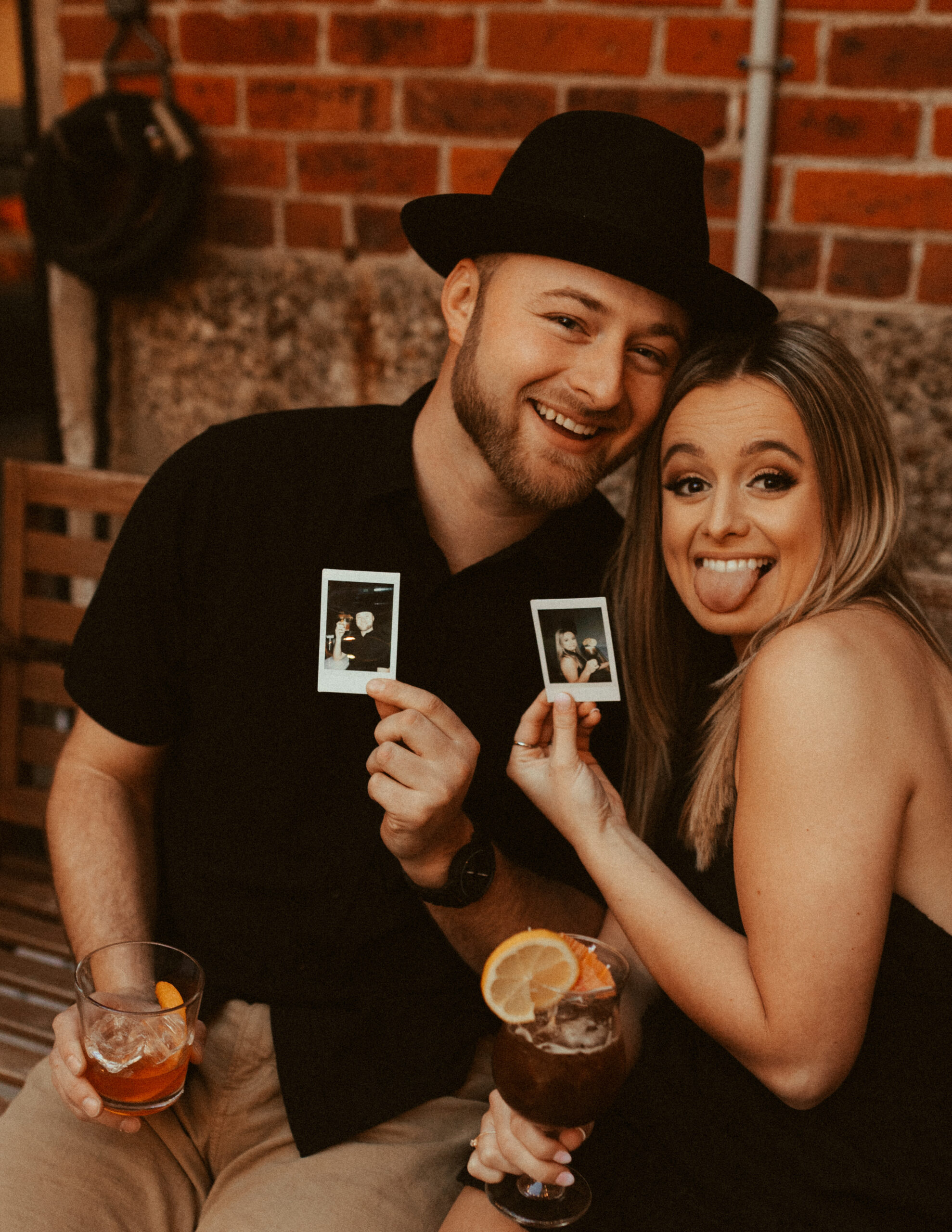 couple smiling at camera holding polaroids during cincinnati engagement photo shoot