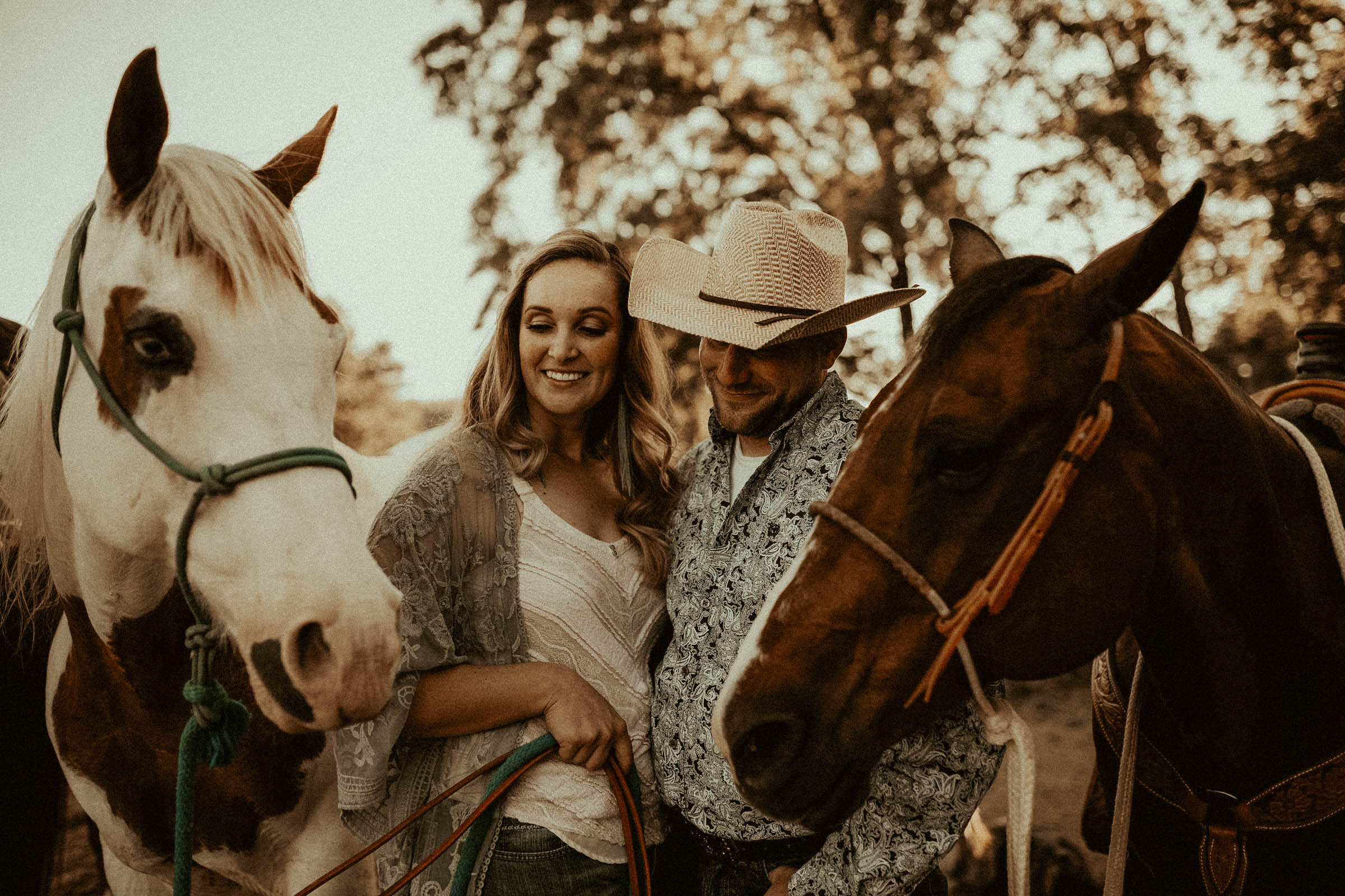 couple standing with horses during engagement photos