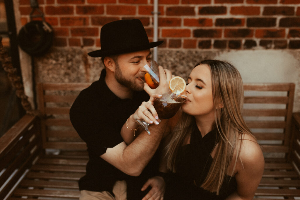 couple sitting on bar swing drinking coctails during cincinnati engagement photos