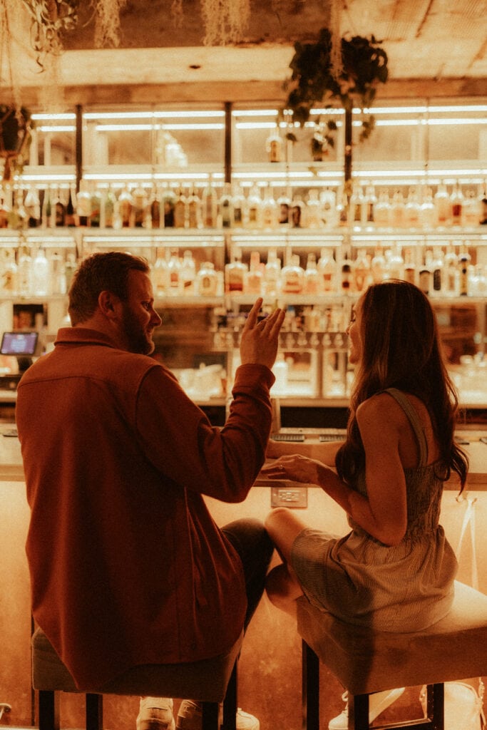 engagement photo of couple laughing and singing at cincinnati cocktail bar, the comfort station