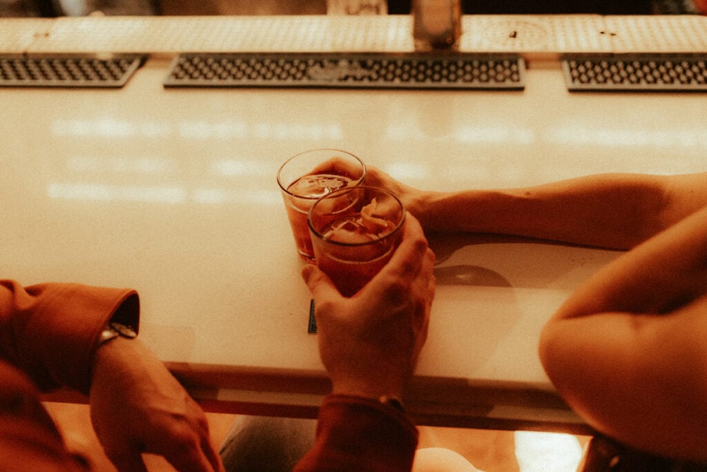 couple holding old fashioned drinks together for cocktail inspired engagement photos