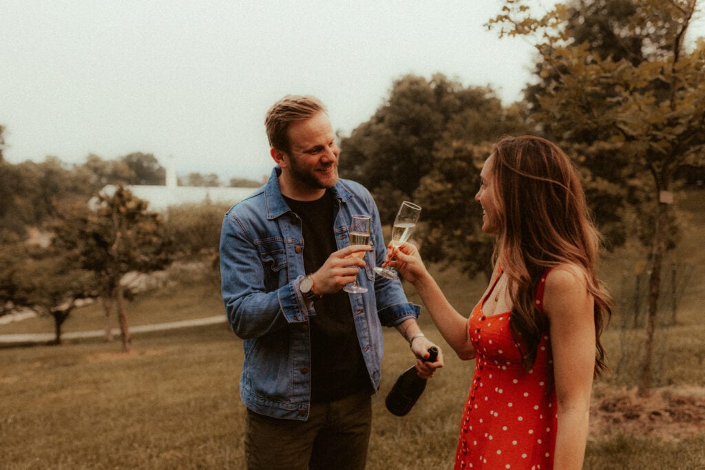 engagement photo of couple doing a cheers after candid champagne pop