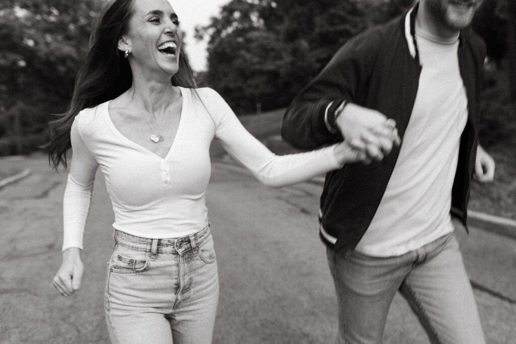 candid engagement photo of couple running hand in hand