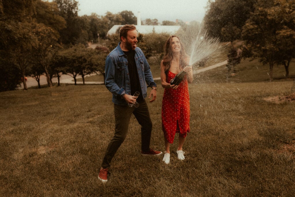 engagement photo of couple popping a bottle of champagne